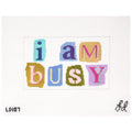 Needlepoint canvas with the phrase 'i am busy' using colorful ransom letters on a white background.