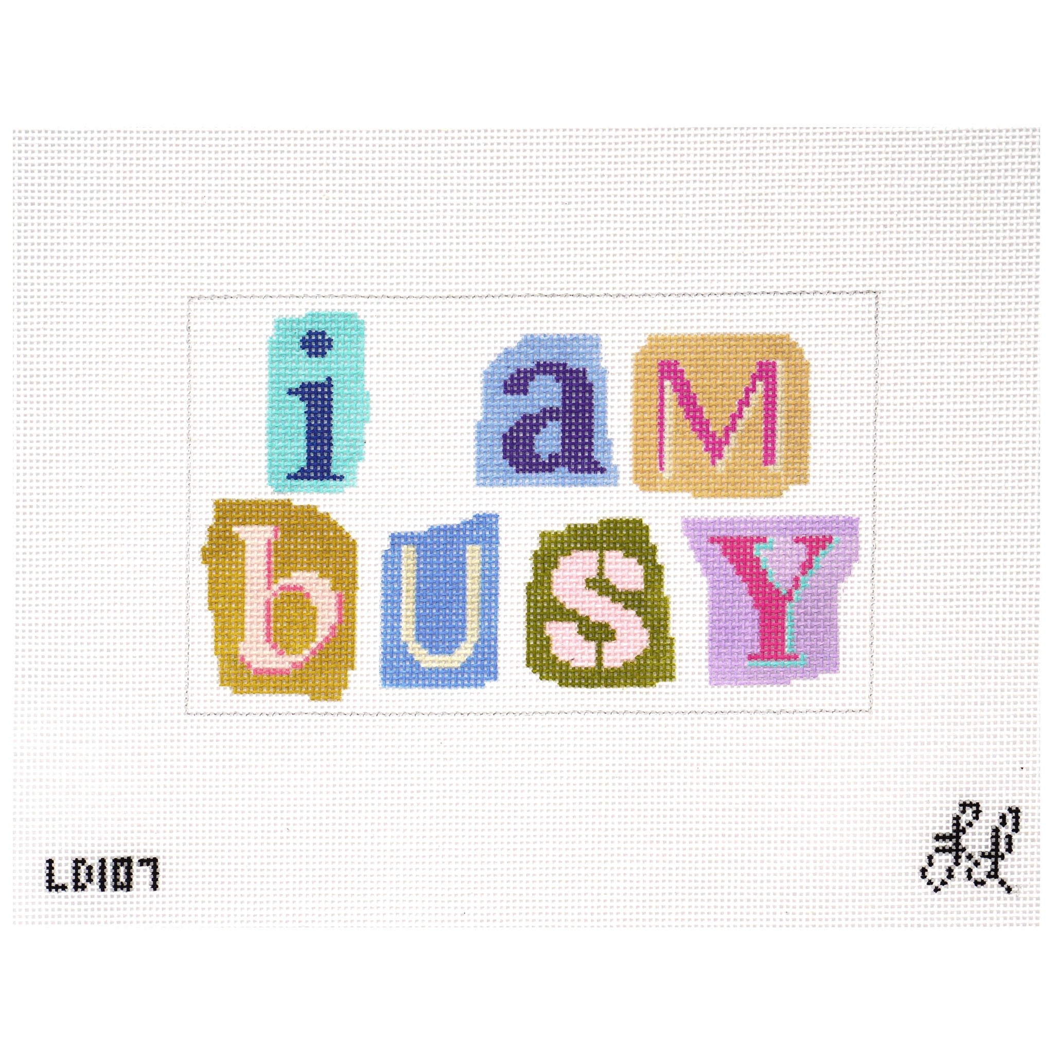 Needlepoint canvas with the phrase 'i am busy' using colorful ransom letters on a white background.