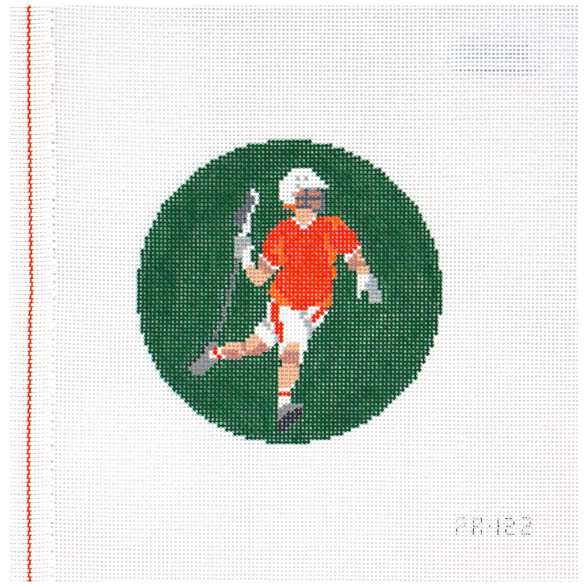 Needlepoint canvas of a lacrosse player in an orange jersey on a green circle with a white background.
