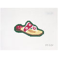 Needlepoint canvas of a pink sandal on a green background