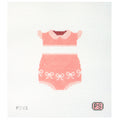 Needlepoint canvas of a pink baby outfit on a white background